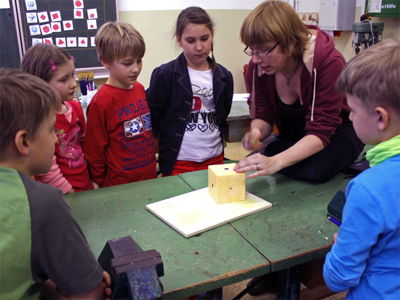 Holzgestalterin Julia Franke erlutert den Grundschlern im Werkraum der Schule, welche Kristallformen in einem Wrfel versteckt sind. Foto: Ralph Sontag